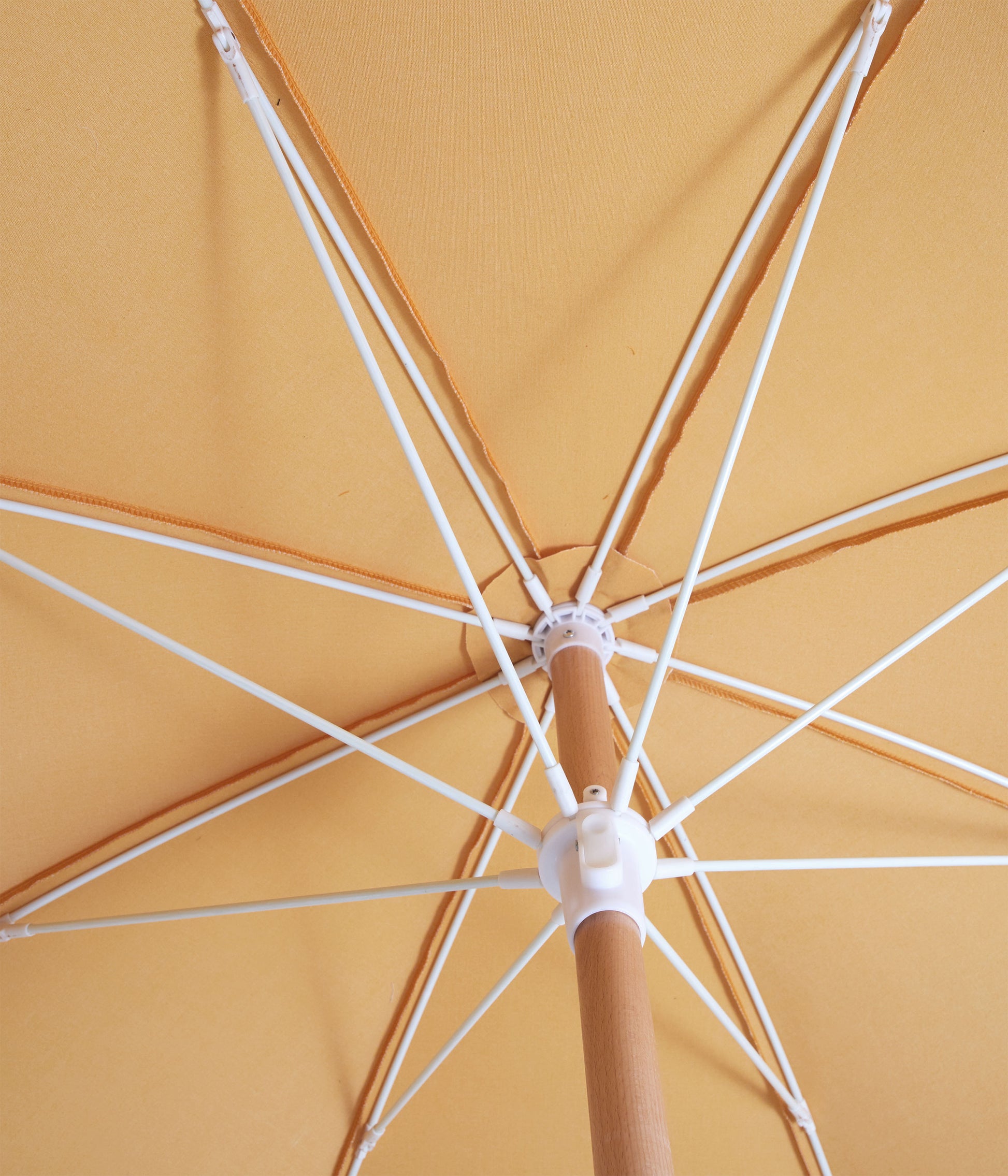 Sunday Supply Co Golden beach umbrella open and seen from underneath.