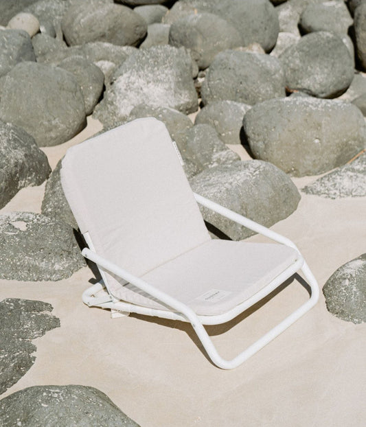 Dunes beach chair set up on sand beside a beach umbrella