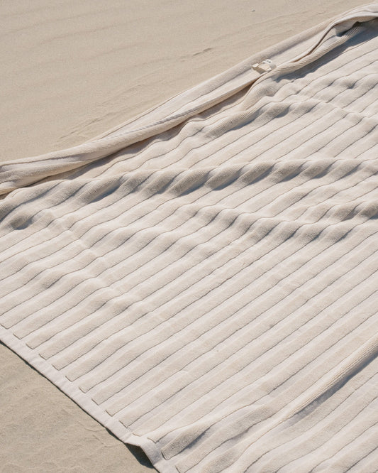 Cream ribbed towel spread over sand.