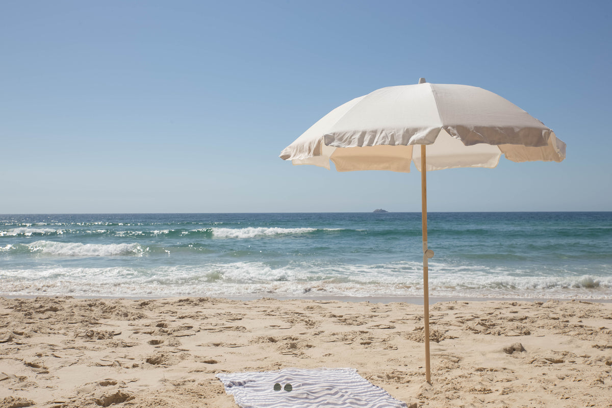 Dunes Splice Beach Umbrella and striped towel on a sandy beach