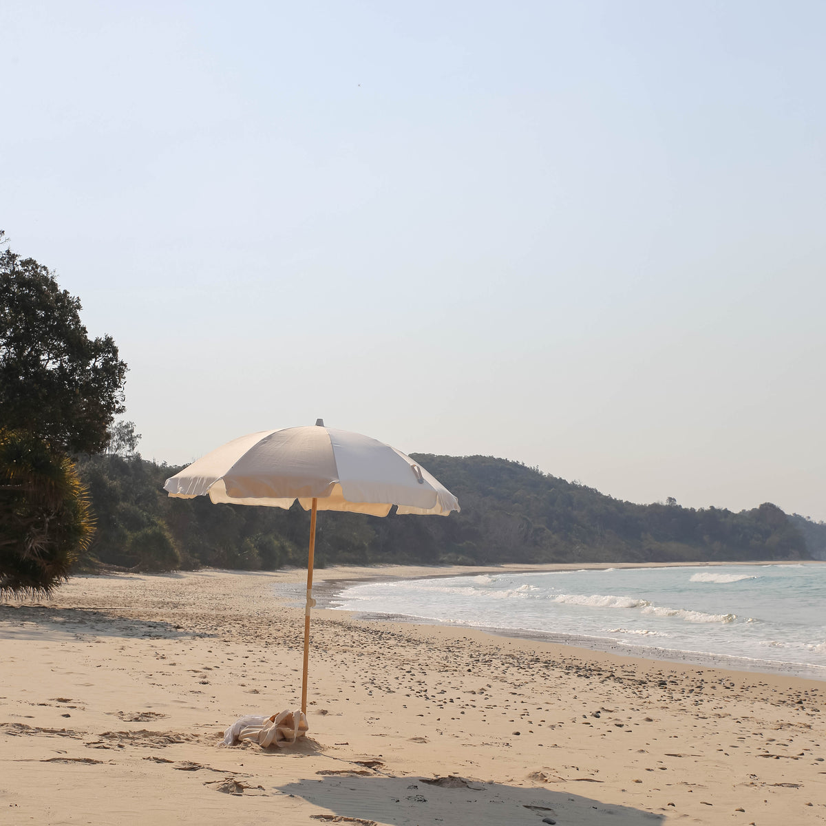 Dunes Splice Beach Umbrella on a quiet beach with a wooded headland
