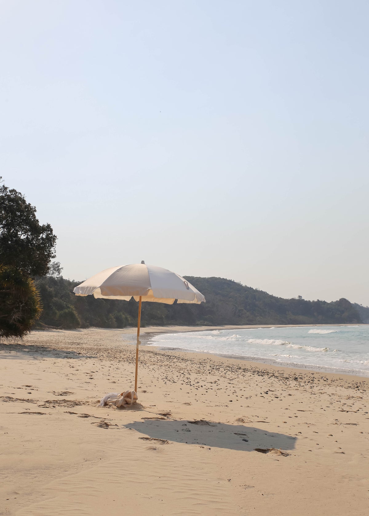 Dunes Splice Beach Umbrella on a quiet beach with a wooded headland