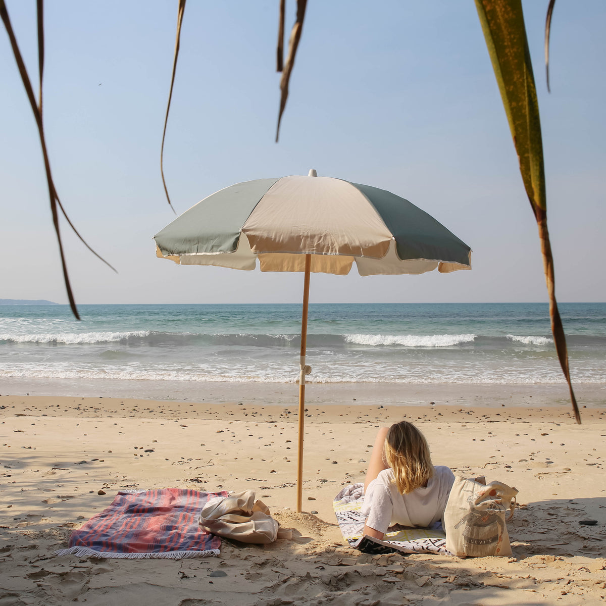 Relaxed beach scene beneath a Tallow Splice Beach Umbrella