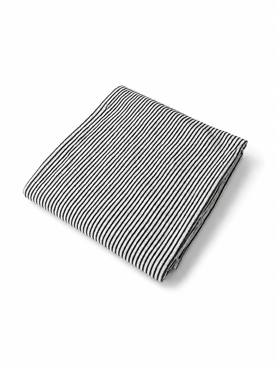 Folded black and white striped beach towel viewed at an angle on a white background.