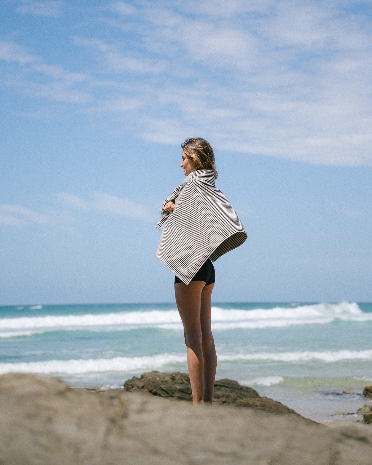 Black striped beach towel wrapped around a model's shoulders.